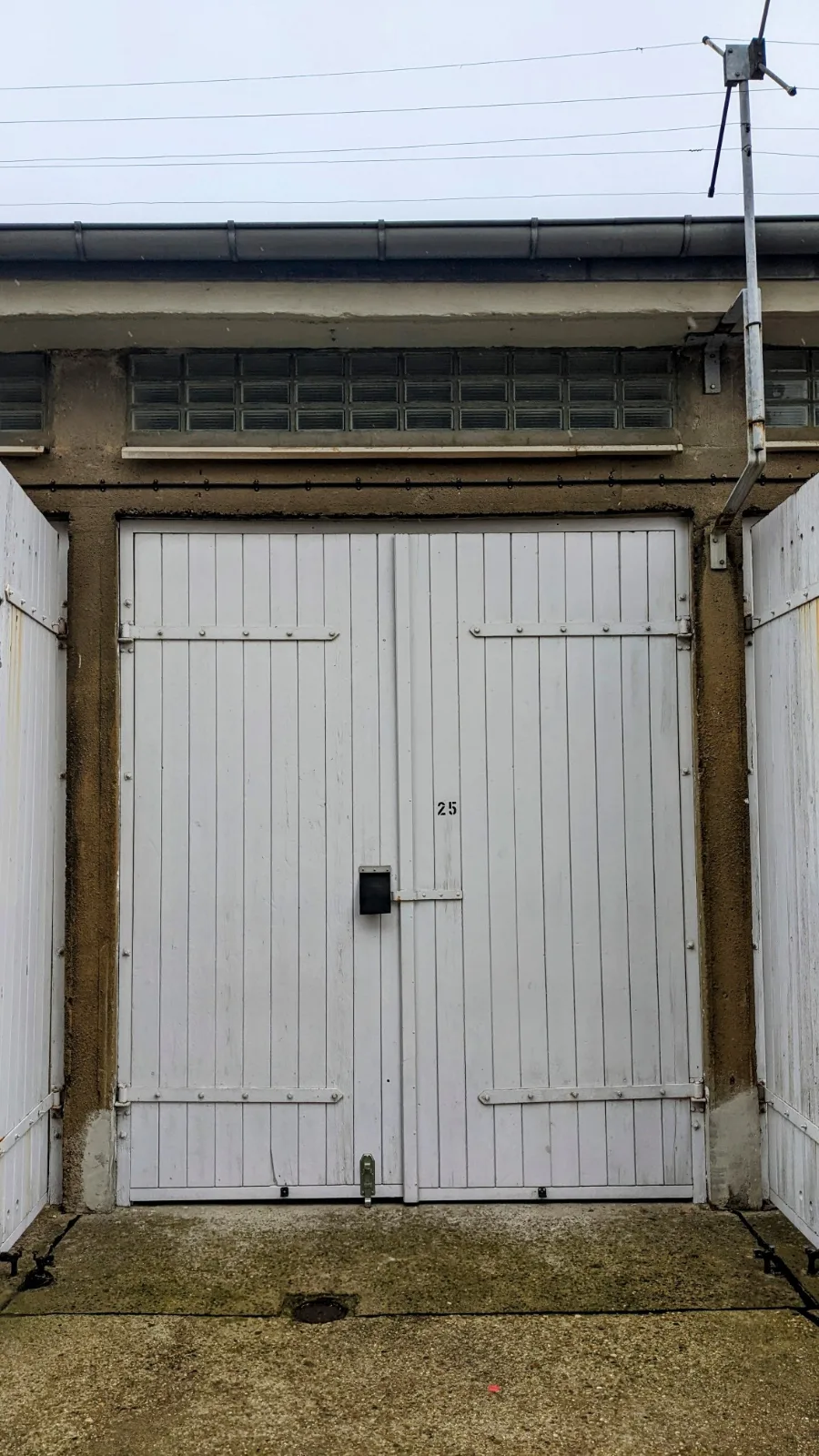 Weißes Garagentor mit der Nummer 25 in einem Garagenhof bei der Gedenkstätte Hohenschönhausen