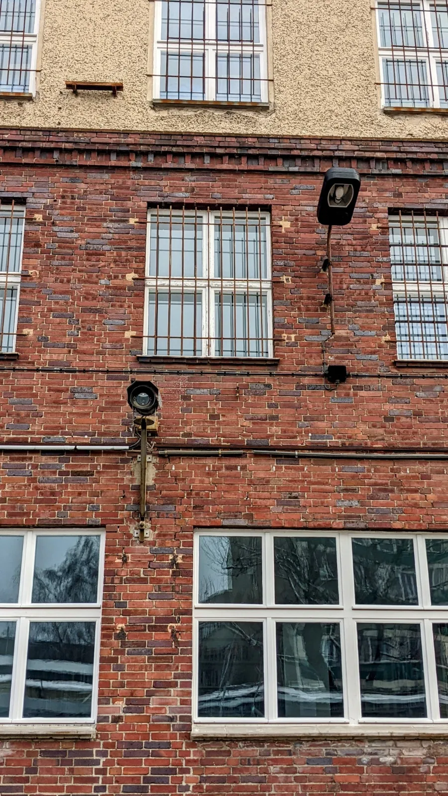 Klinkerfassade mit vergitterten Fenstern und Außenlampen an der Gedenkstätte Hohenschönhausen