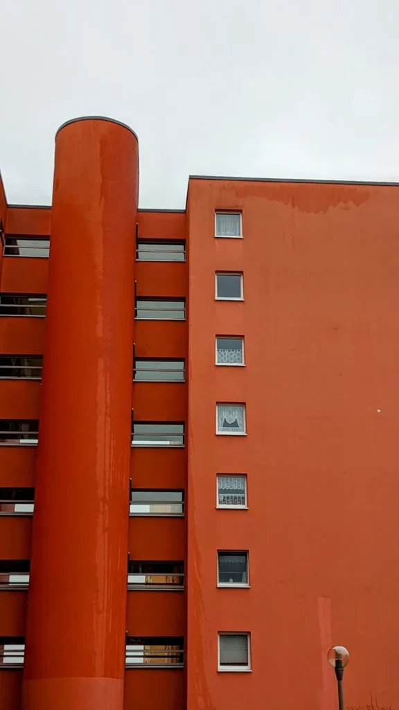 Orangerotes Wohnhochhaus mit rundem Treppenturm und Balkonen im Brunnenviertel von Gesundbrunnen