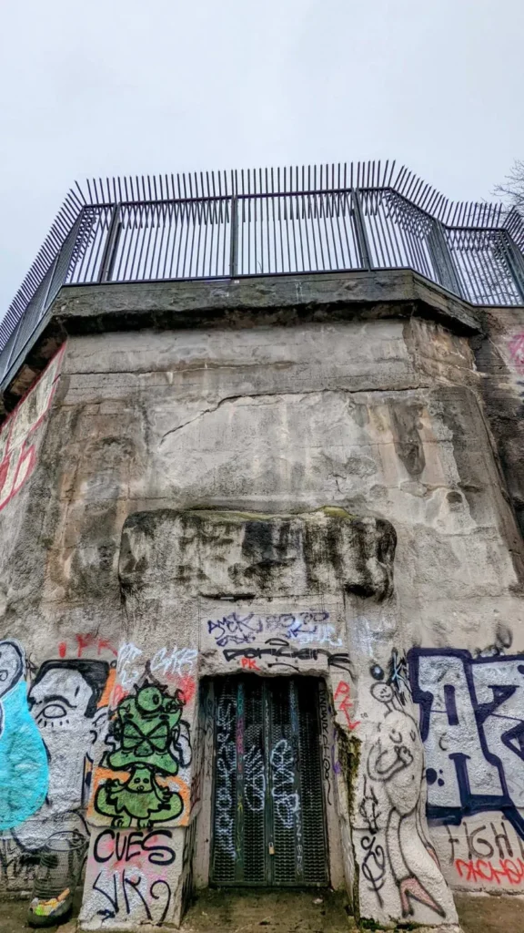 Betonwand des Flakturms im Humboldthain mit Graffiti, vergitterter Tür und Geländer der Aussichtsplattform
