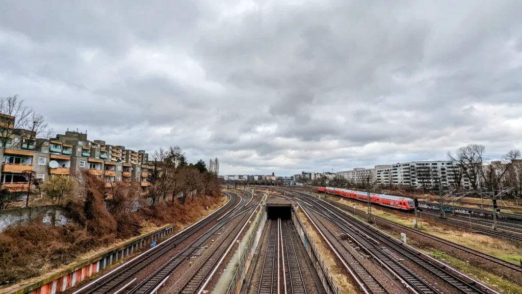Breites Gleisfeld am Bahnhof Gesundbrunnen mit einem Zug und Wohnhäusern am Rand