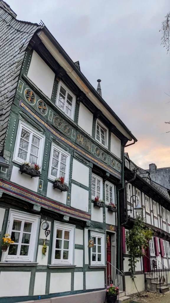 Fachwerkhaus mit grünen Verzierungen und weißen Sprossenfenstern, daneben weitere Fachwerkhäuser