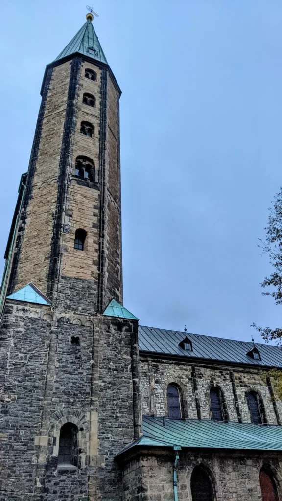 Kirchturm aus Bruchstein mit grün gedecktem Spitzdach neben einem Kirchenschiff
