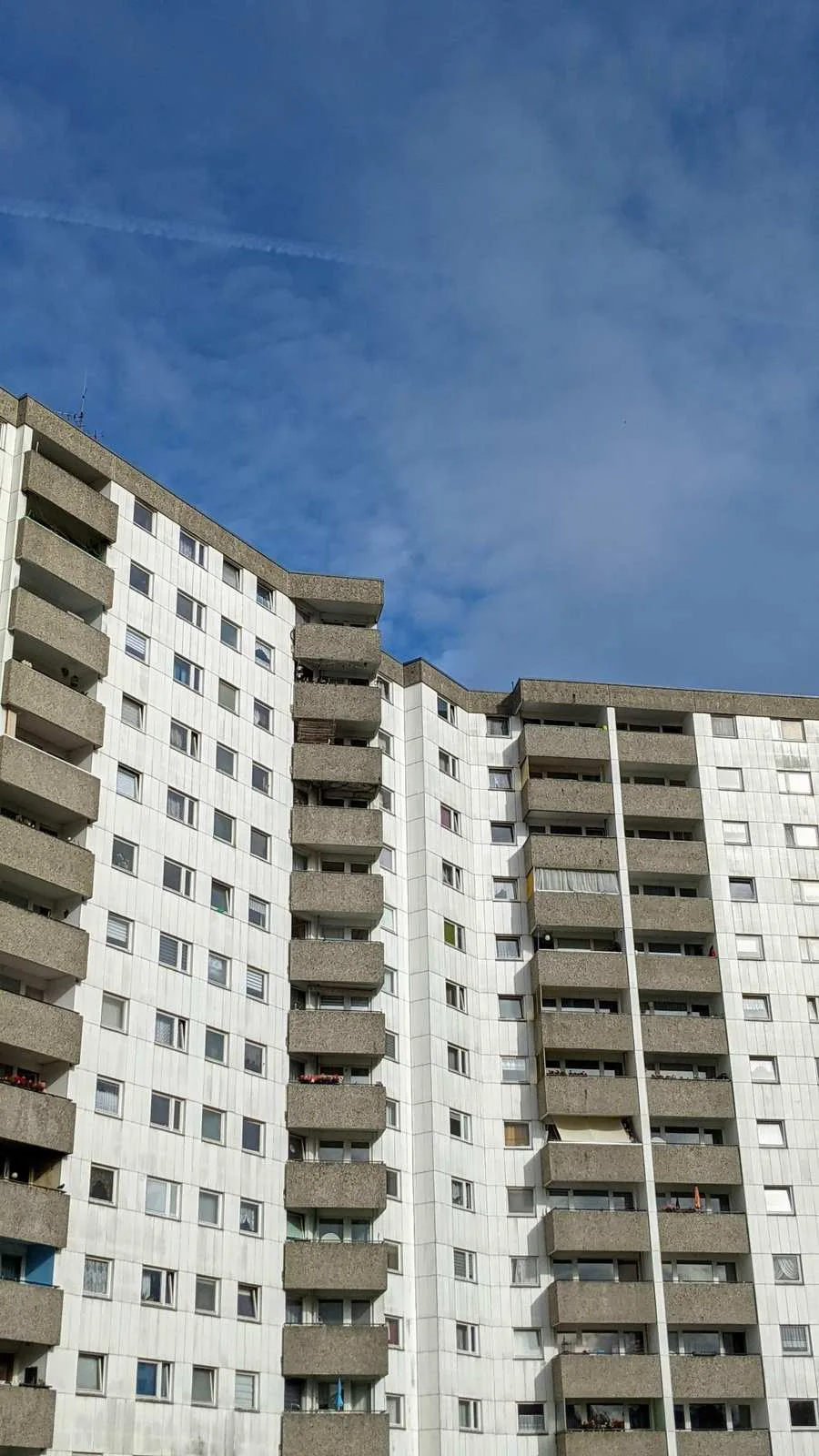Weißgrauer Wohnhochhausriegel mit Balkonreihen vor blauem Himmel in der Gropiusstadt