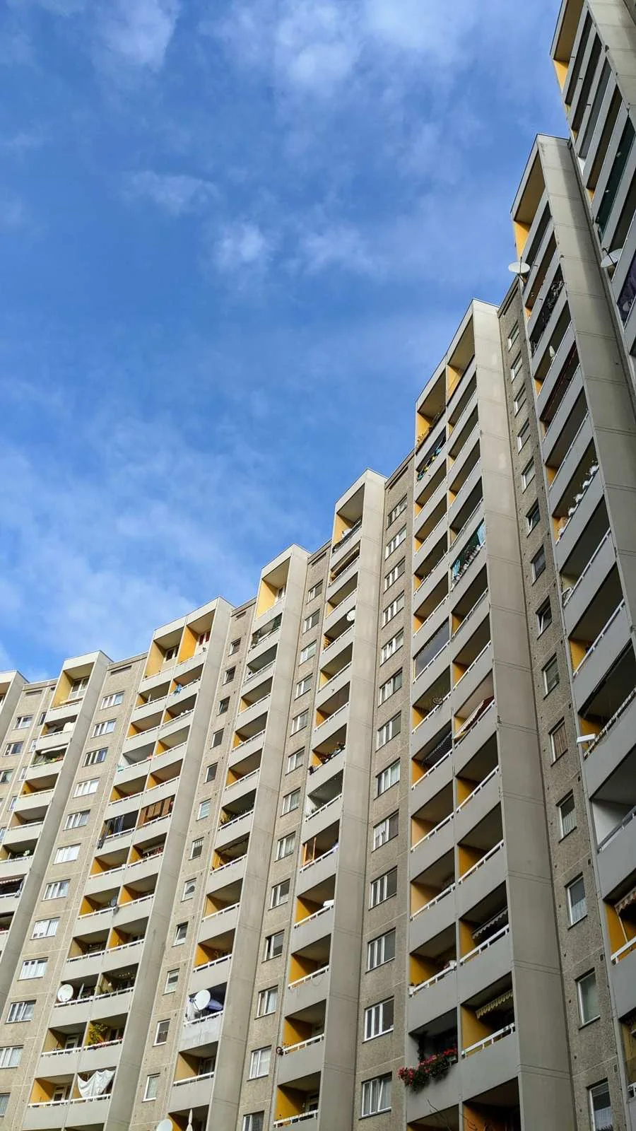 Geschwungener Wohnhochhausriegel mit regelmäßigen Balkonen vor blauem Himmel in der Gropiusstadt