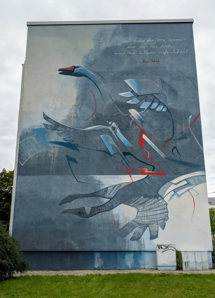 Wandbild von Guido Zimmermann an der Sternstraße in Lutherstadt Wittenberg: weißer Schwan über blau-grauen Vögeln, darüber ein Zitat von Jan Hus