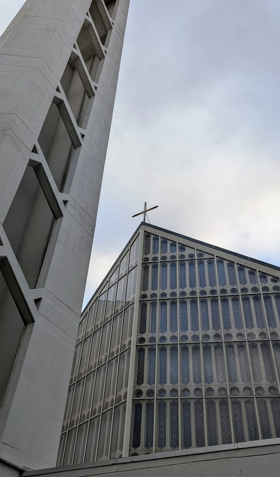 Giebelfront einer Nachkriegskirche mit Kreuz und Glaswand neben einem freistehenden Betonturm, Nestorstraße in Halensee