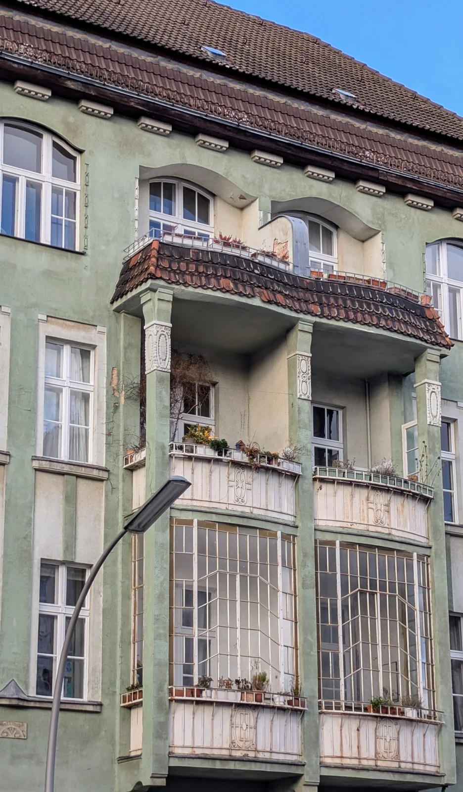 Grün gestrichener Altbau mit Erker, Balkonen und Ornamenten
