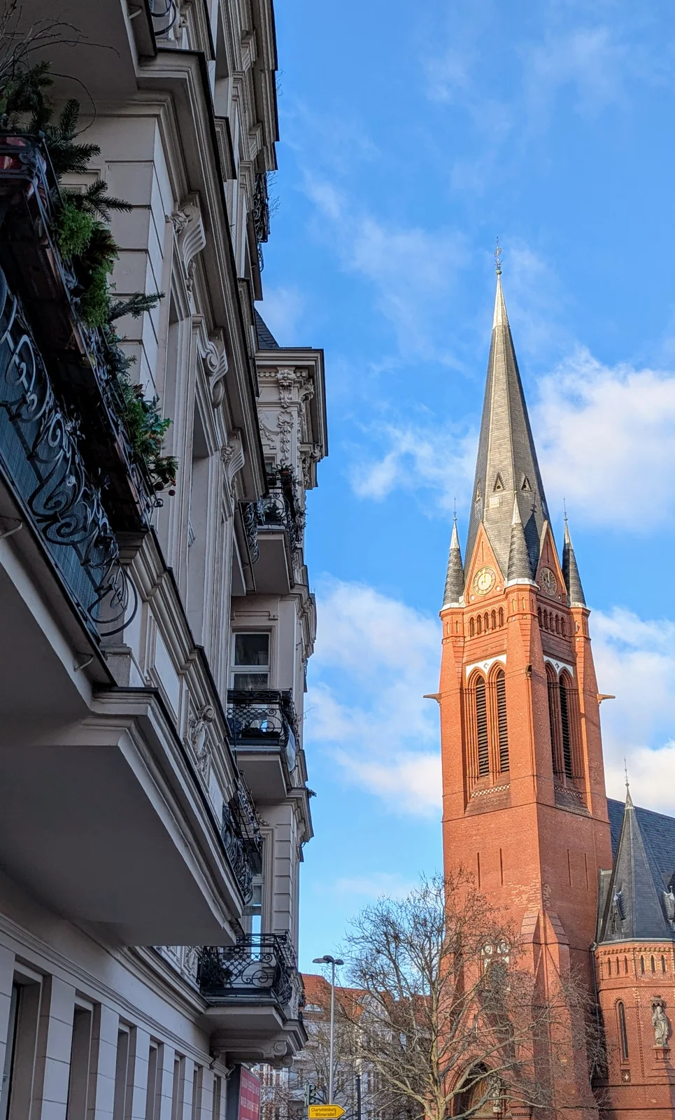 Roter Backsteinturm mit spitzem Helm zwischen Altbauten