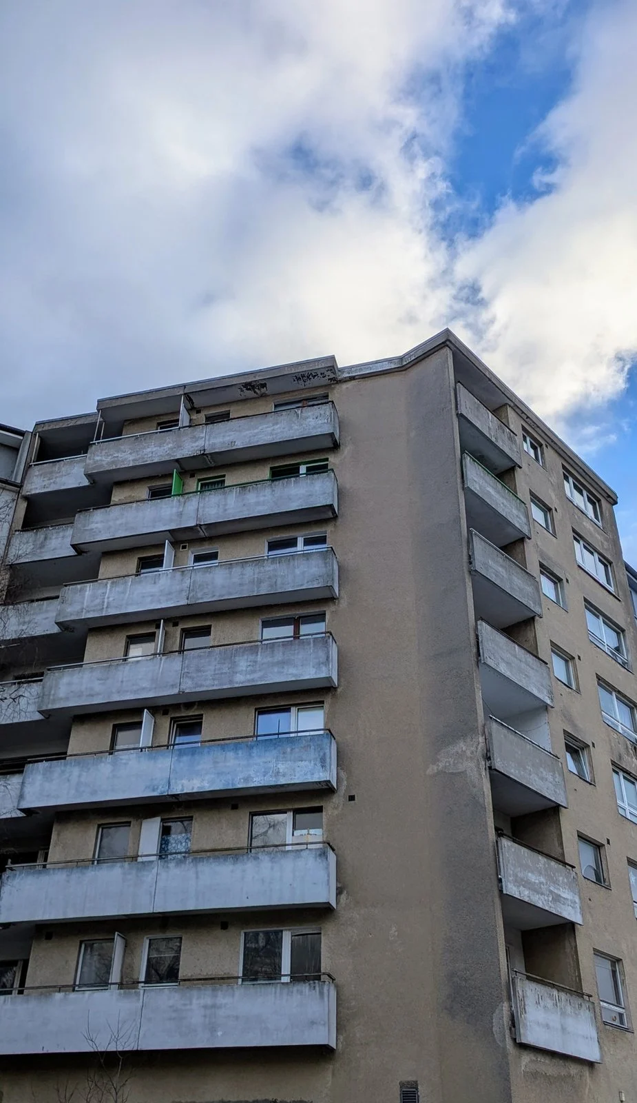 Graues Wohnhochhaus aus Beton mit durchgehenden Balkonbändern vor Wolkenhimmel, aufgenommen auf der Tour durch Halensee