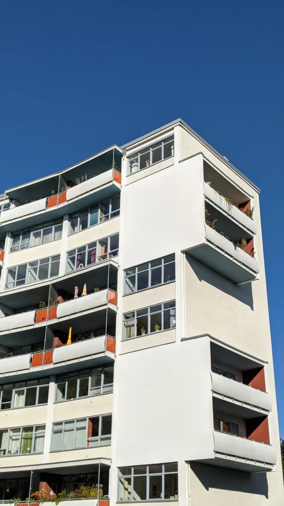 Weißes Wohnhochhaus der Interbau an der Händelallee mit Loggien und vorspringenden Balkonen vor blauem Himmel