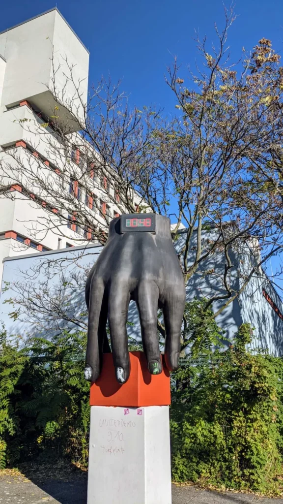 Große Metallhand von Joachim Schmettau hält einen Block auf rot gefasstem Sockel an der Altonaer Straße