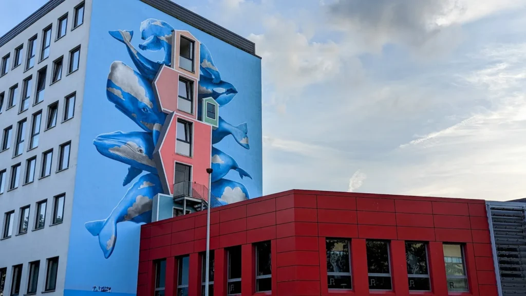 Bürogebäude am Harburger Ring 17 mit dem Wal-Wandbild von Nevercrew, davor ein roter Anbau