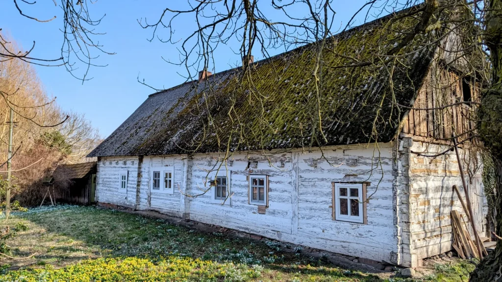 Niedriges weißes Haus mit moosbewachsenem Dach