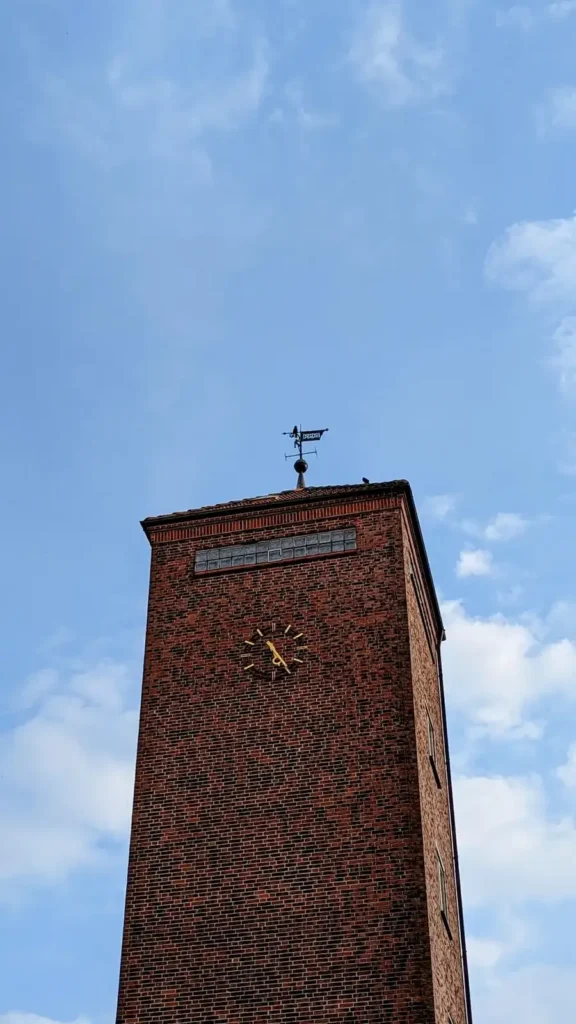 Backsteinturm mit Uhr und Wetterfahne am Bürgerhaus in Heide