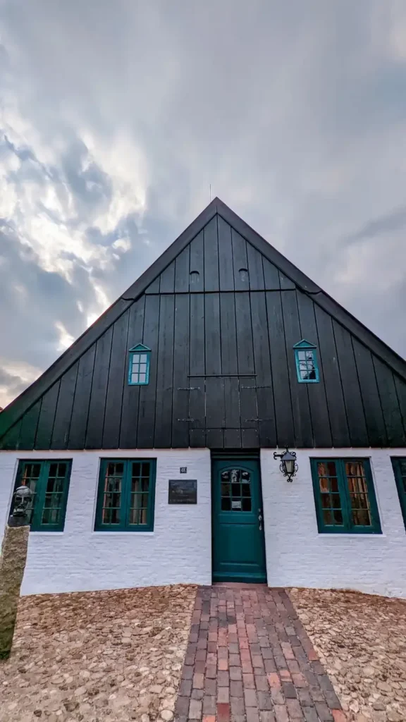 Klaus-Groth-Haus in Heide: Steilgiebel mit dunkler Verschalung über weißem Erdgeschoss und grüner Tür