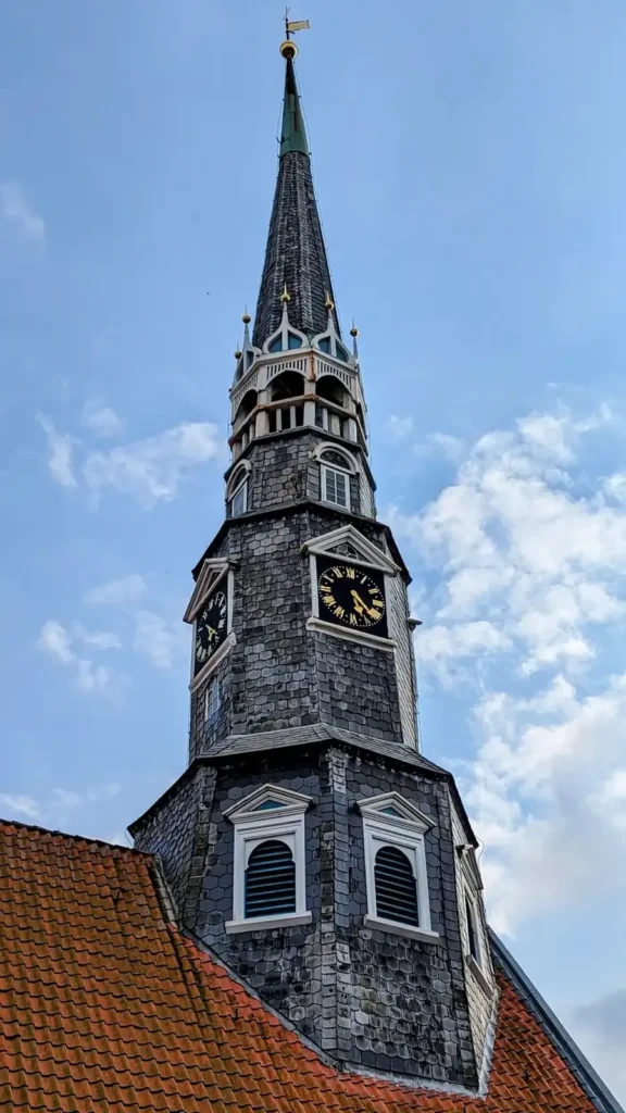 Turmspitze der St.-Jürgen-Kirche in Heide mit Schieferhaube, Uhrblättern und Laterne
