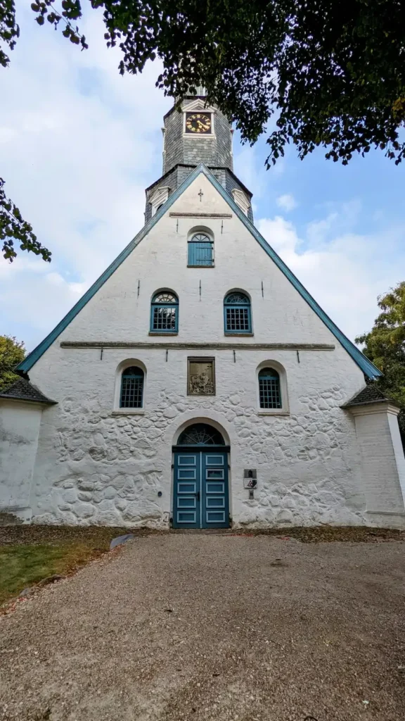 Westgiebel der St.-Jürgen-Kirche in Heide mit blauem Portal und Uhrturm darüber