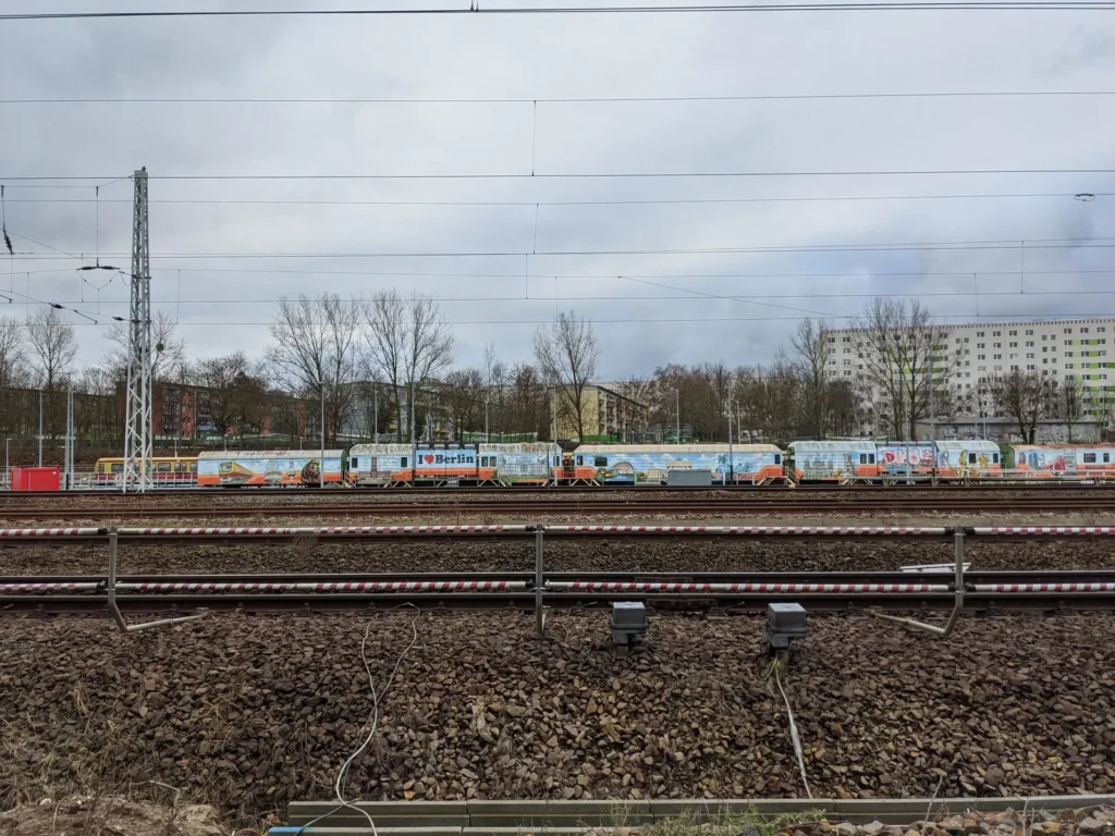 Blick vom Bahnweg in Berlin-Friedrichsfelde auf Gleise, Oberleitung und einen abgestellten Zug