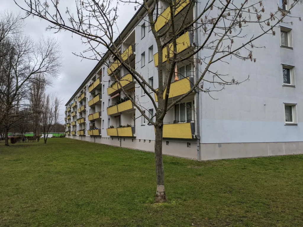 Fünfgeschossige Wohnzeile mit gelben Balkonen und Rasen davor in Berlin-Friedrichsfelde