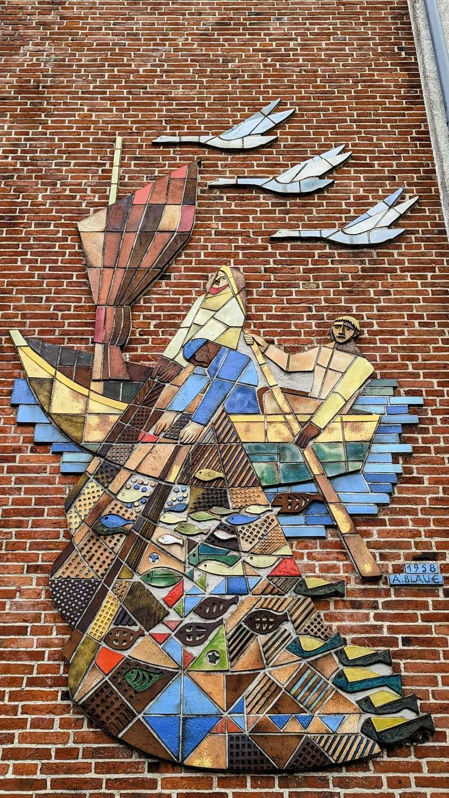 Mosaik mit zwei Fischern im Boot und fliegenden Möwen an einer Backsteinwand in Husum