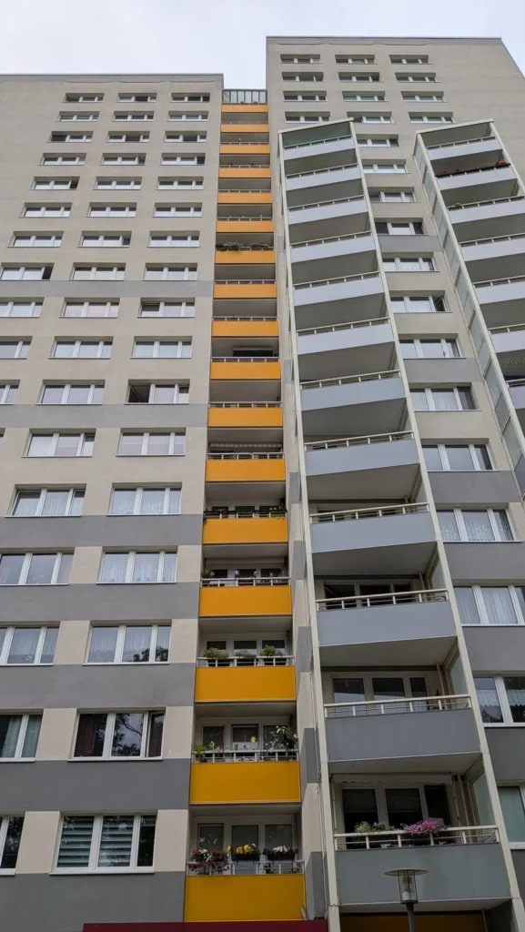 Hochhaus an der Dathepromenade in Berlin-Friedrichsfelde mit orangefarbenem Balkonband zwischen grauen Flächen