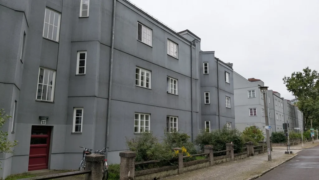 Graue und rote Häuser der Splanemann-Siedlung an einer Straße in Berlin-Friedrichsfelde