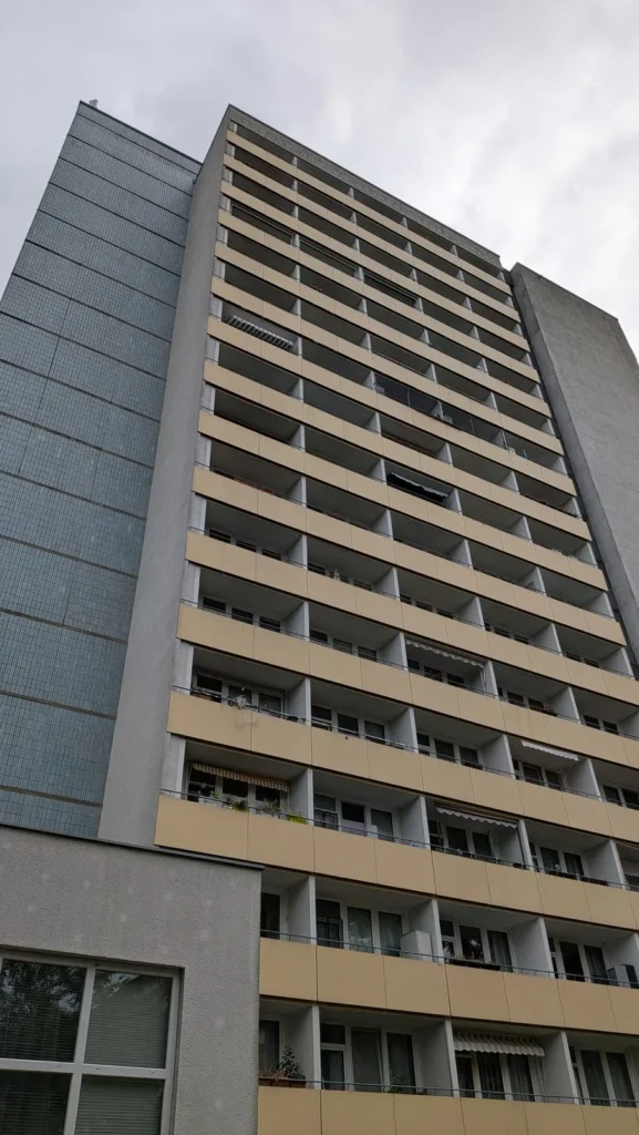 Hochhaus an der Volkradstraße in Berlin-Friedrichsfelde mit beigen Balkonbändern und blaugrauer Fliesenseite