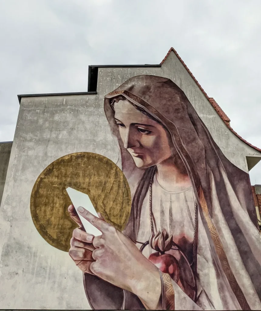 Wandbild Media Magdalena von Innerfields an der Mittelstraße in Lutherstadt Wittenberg: Frau im Schleier mit goldener Scheibe hinter dem Kopf blickt auf ein Smartphone