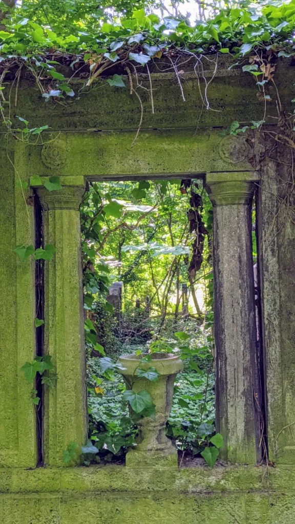Durchblick durch eine bemooste Grabwand auf dem Jüdischen Friedhof Weißensee