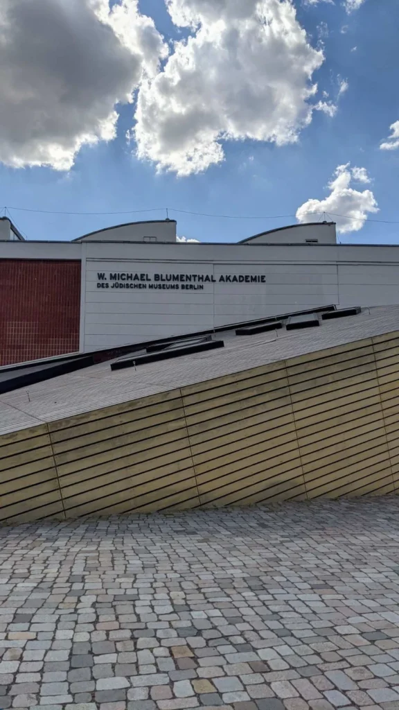 W. Michael Blumenthal Akademie des Jüdischen Museums Berlin, flacher heller Hallenbau mit Schriftzug, davor ein schräg aufsteigender Baukörper