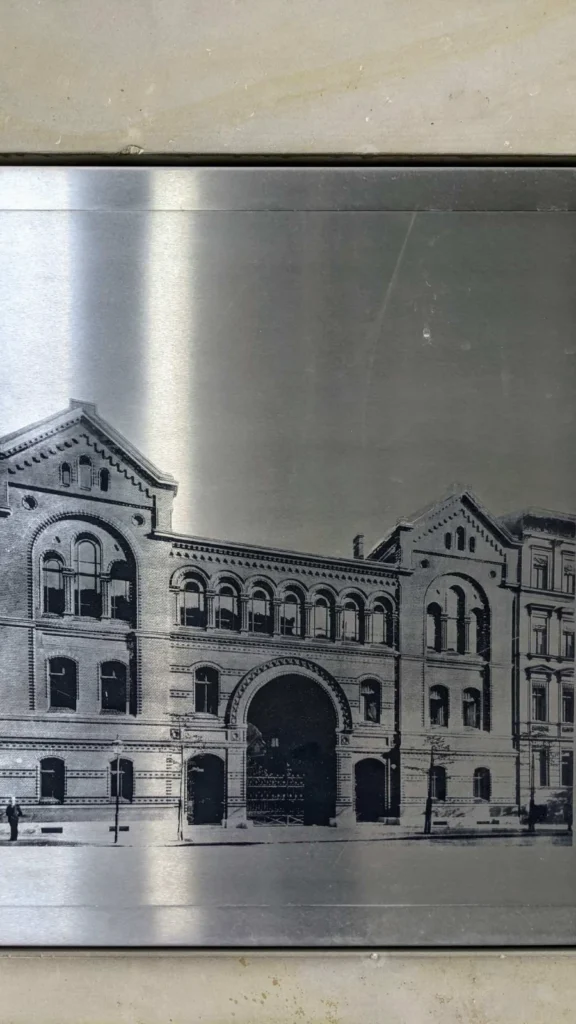 Metalltafel mit eingeätzter historischer Ansicht der Synagoge Lindenstraße an der Zufahrt Axel-Springer-Straße 48 bis 50