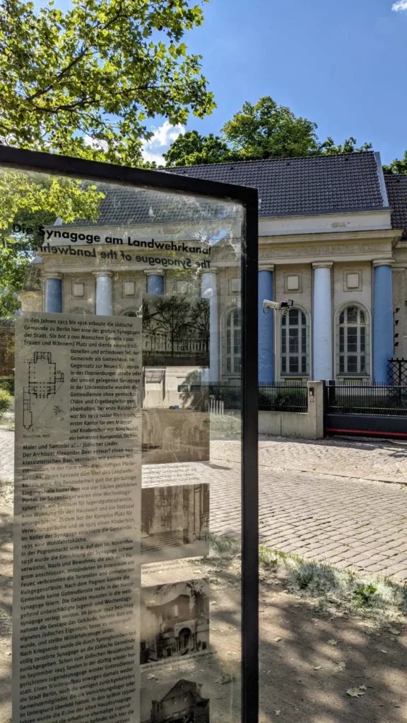 Gläserne Infostele Die Synagoge am Landwehrkanal vor dem Seitenflügel der Synagoge Fraenkelufer mit blauen Säulen und Rundbogenfenstern