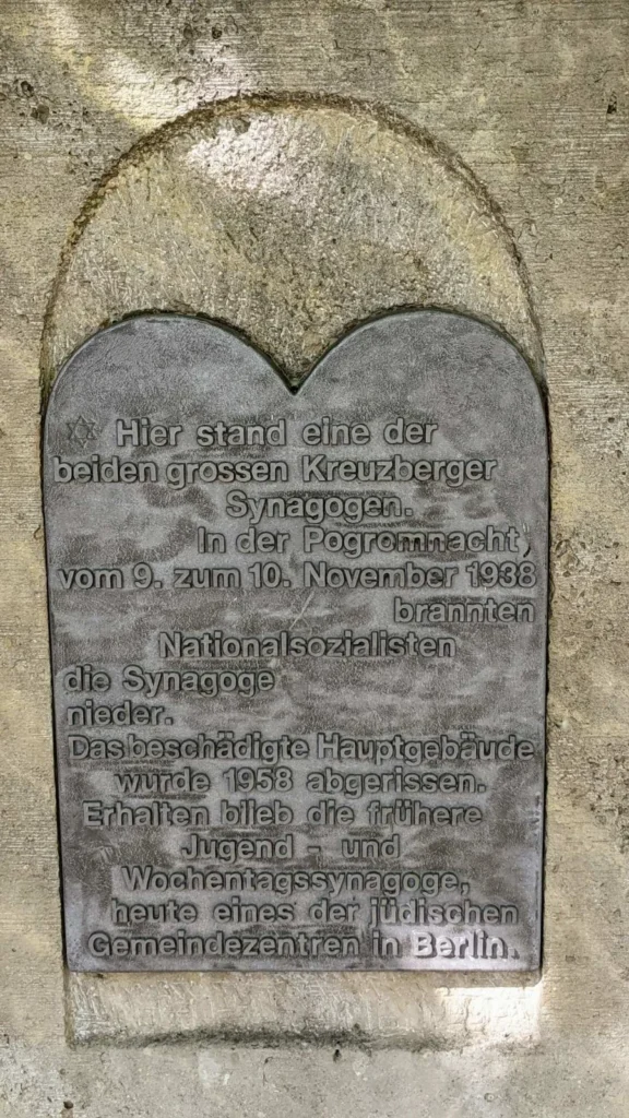 Dunkle Metalltafel in Form der Gesetzestafeln in einer Bogennische am Fraenkelufer, links oben ein kleiner Davidstern