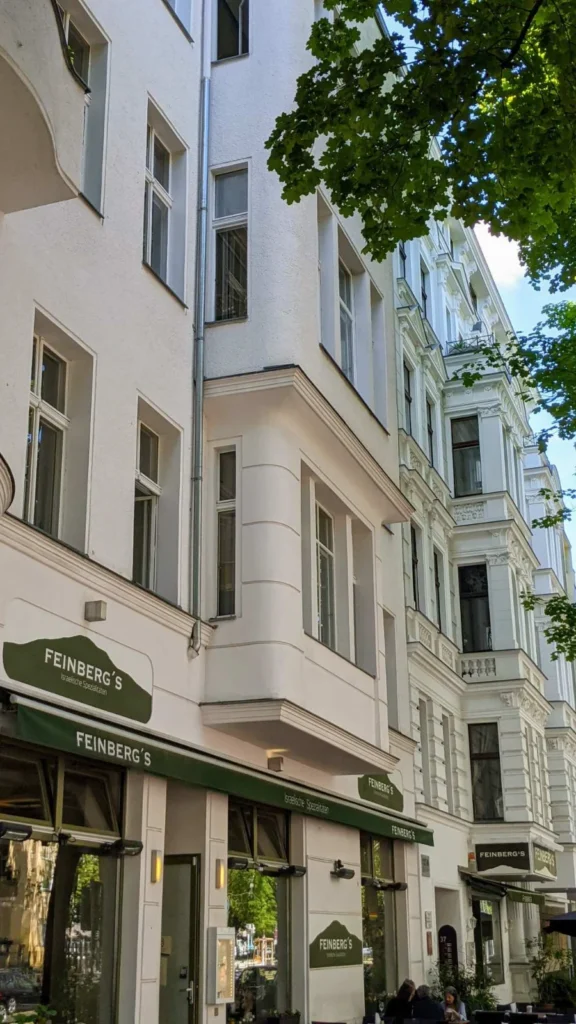 Helle Gründerzeitfassaden in der Fuggerstraße mit dem Lokal Feinberg's, Israelische Spezialitäten, unter einer grünen Markise