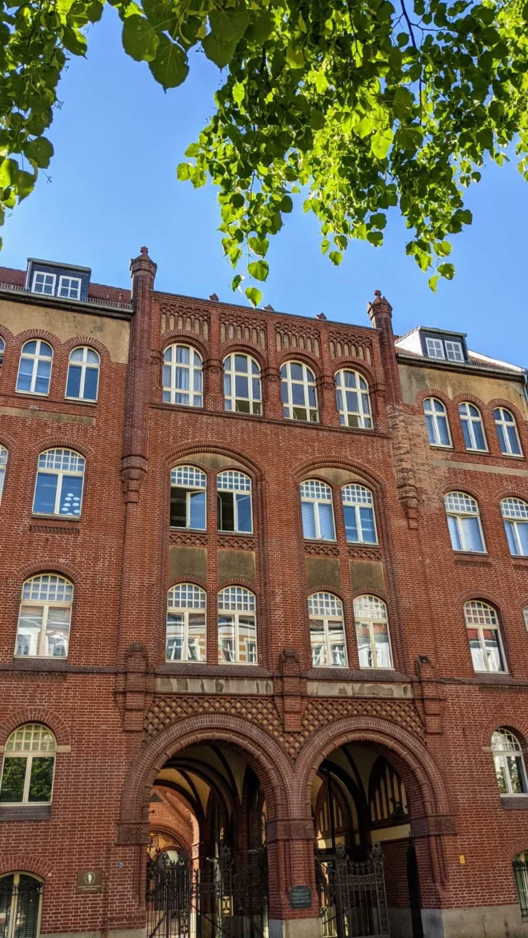 Vorderhaus der Synagoge Rykestraße 53 aus rotem Backstein mit Doppelbogen-Durchfahrt und Davidsternen in den Torgittern