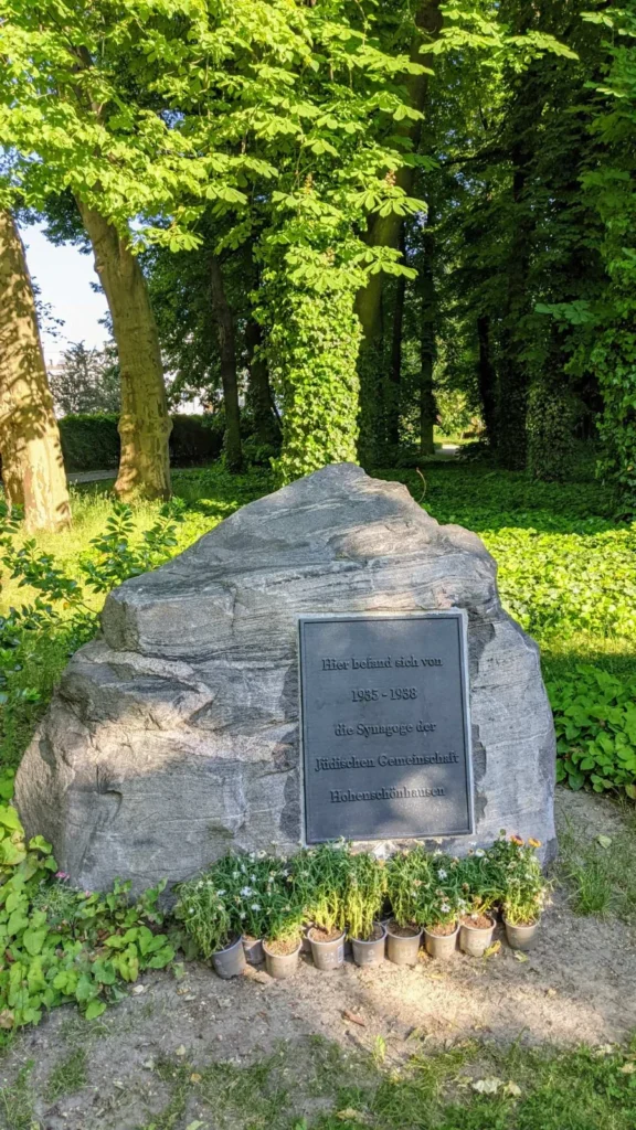 Findling mit Metalltafel für die Synagoge Hohenschönhausen an der Konrad-Wolf-Straße, davor Blumentöpfe