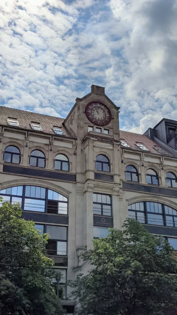 Giebel eines historischen Geschäftshauses mit roter Uhr am Hausvogteiplatz