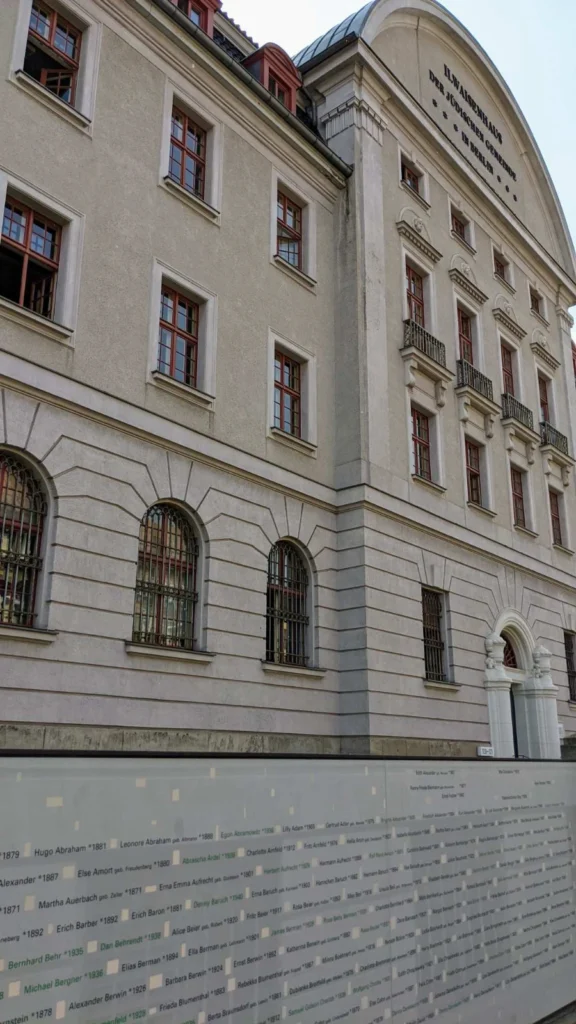 Gedenkwand mit Namen und Geburtsjahren vor dem Giebel des früheren Waisenhauses in Pankow, ein Teil der Namen in grüner Schrift