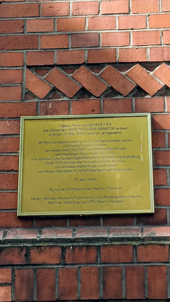 Metallene Gedenktafel für das jüdische Lehrlingsheim Pankow an einer roten Backsteinwand