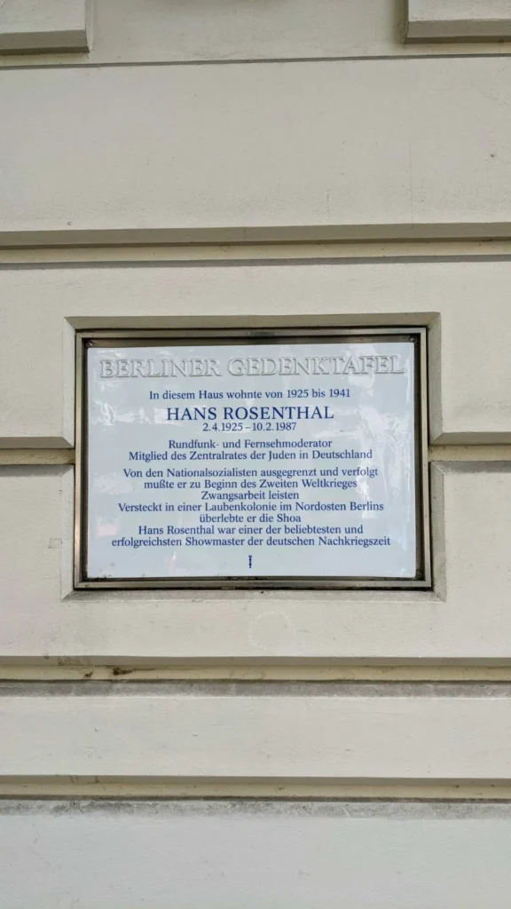 Weiße Berliner Gedenktafel für Hans Rosenthal an einer gequaderten Hauswand in der Winsstraße
