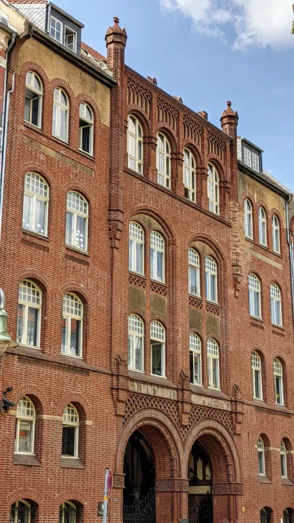 Fünfgeschossiger roter Backsteinbau mit zwei Rundbogentoren, das Vorderhaus der Synagoge Rykestraße