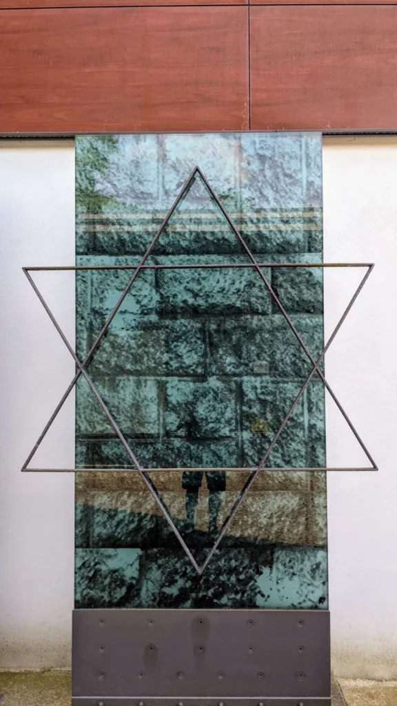 Grüne Glasstele mit einem Davidstern aus Metallstäben am Eingangsbereich des Jüdischen Friedhofs Schönhauser Allee