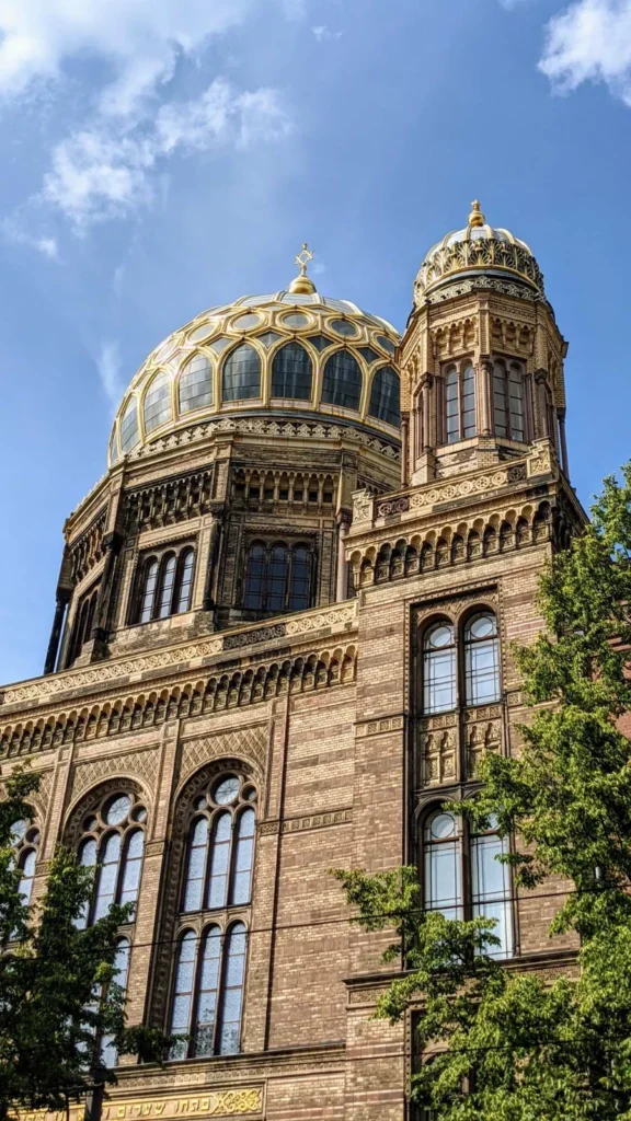 Straßenfront der Neuen Synagoge mit Hauptkuppel und beiden Türmen, über dem Portal ein goldenes hebräisches Schriftband