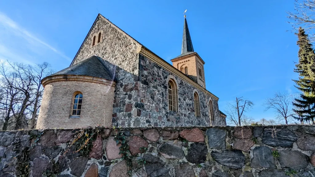 Feldsteinkirche in Jühnsdorf hinter einer Feldsteinmauer