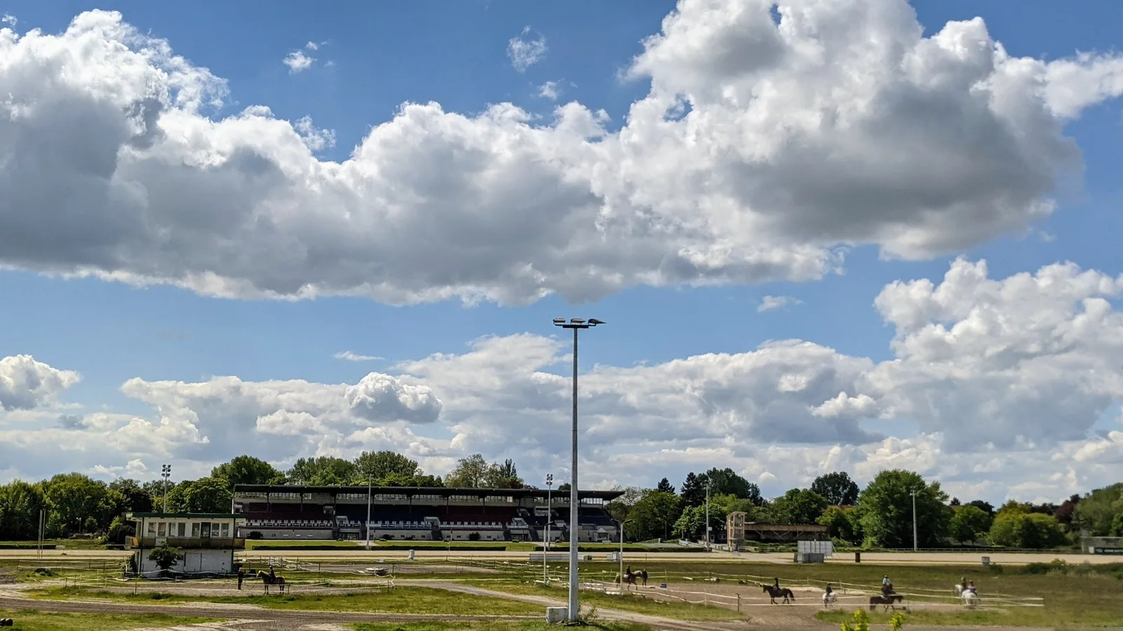 Blick über die Bahn der Trabrennbahn Karlshorst zur Tribüne mit Flutlichtmast
