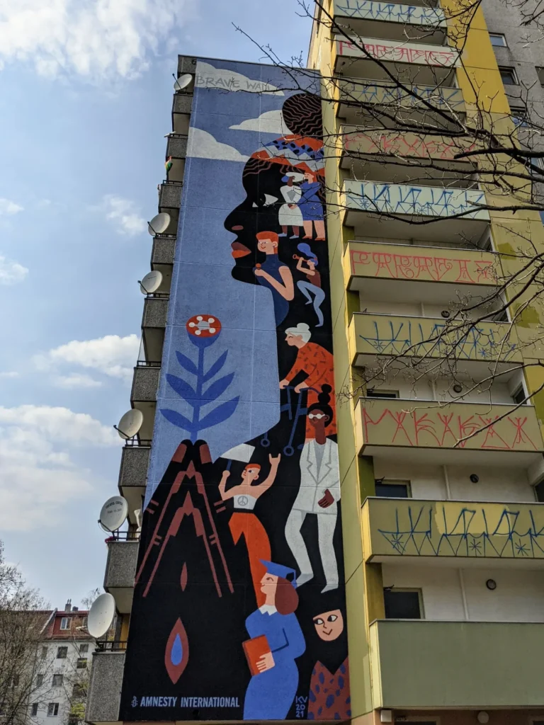 Wandbild Brave Wall von Katerina Voronina an der Gitschiner Straße in Berlin-Kreuzberg: schwarzes Frauenprofil, in dem Menschen verschiedener Generationen stehen