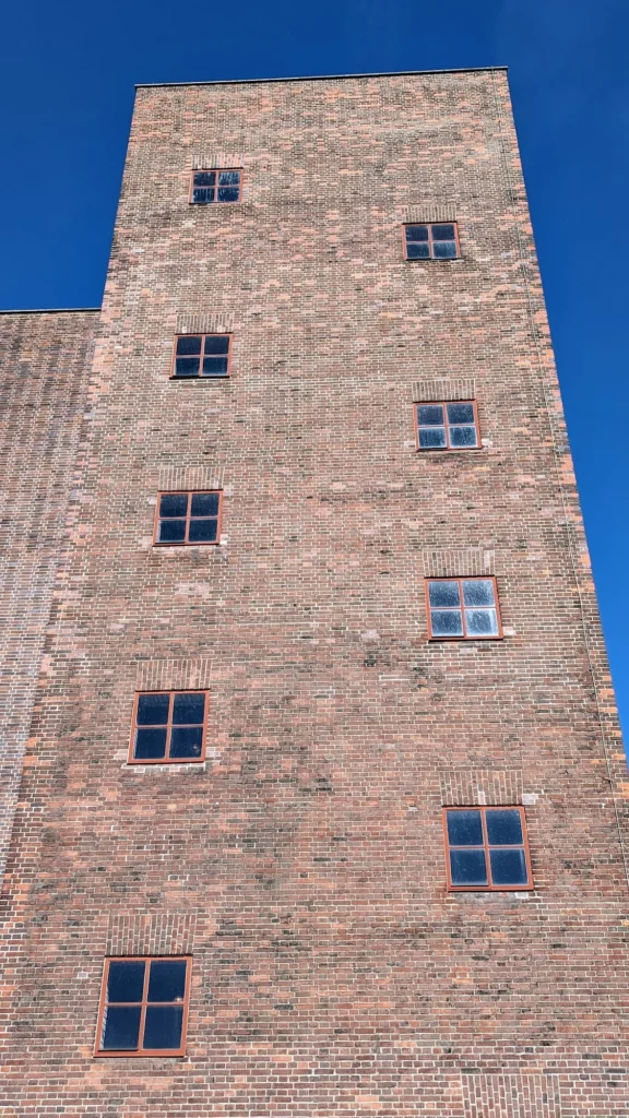 Hoher Backsteinturm mit kleinen Fenstern am Kraftwerk Peenemünde