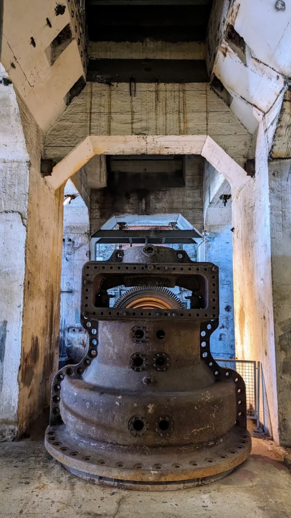 Schwere gusseiserne Maschine unter einem Betontrichter im Kraftwerk