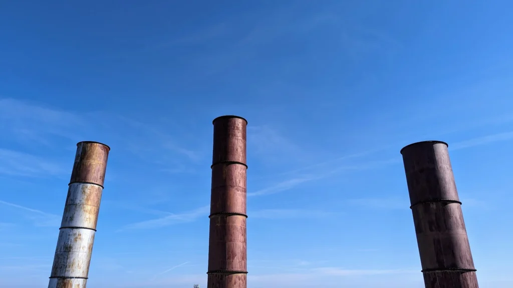 Drei rostige Schornsteine des Kraftwerks vor blauem Himmel